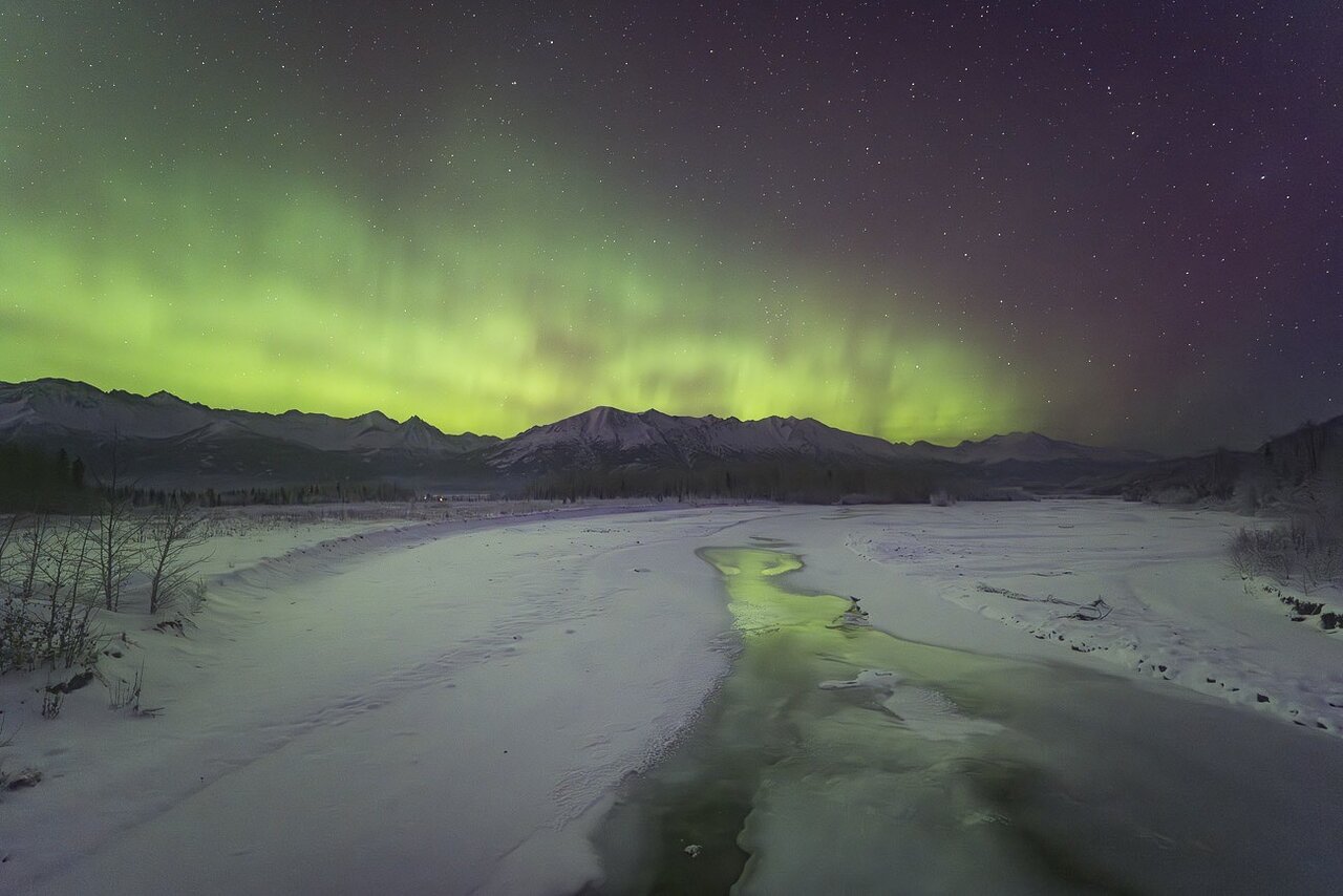 A view of the Northern Lights over a snowy landscape